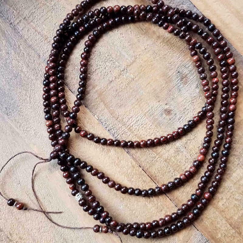 Långt halsband med mörk sandelträ & liten silverdetalj.