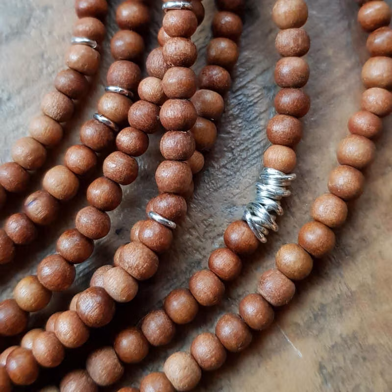 Långt halsband med ljus sandelträ och handgjorda silverdetaljer.