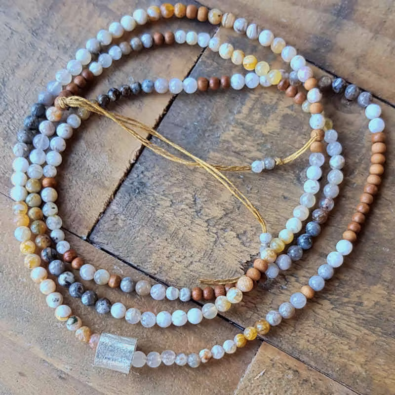 Långt halsband med pärlor av agat i ljusa, jordnära nyanser & ljus sandelträ. Handgjord silverdetalj med borstad yta.