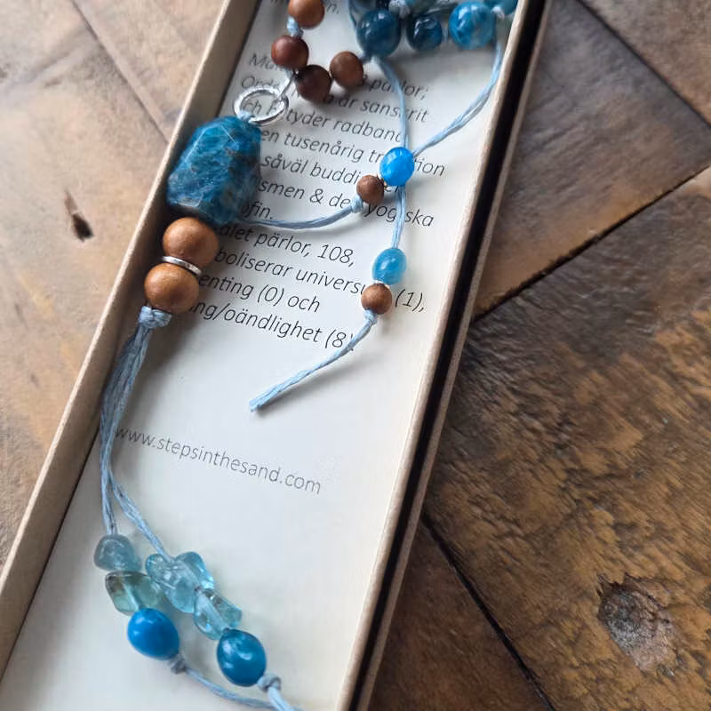 Apatit i levande turkos/blå nyanser samspelar harmoniskt med pärlor av ljus sandelträ.