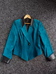 Mockajacka i en djup petrolfräg med svarta skinndetaljer