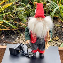 Äldre tomte med lykta och skidor