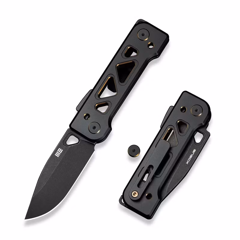 WE Knife Tyro fällkniv med skeletterat svart titanhandtag med guldfärgade kanter och svart blad
