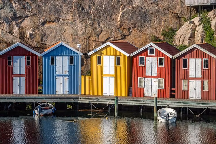 Färgglada sjöbodar på en brygga vid havet illustrerar strandskyddsdispens för sjöbod.