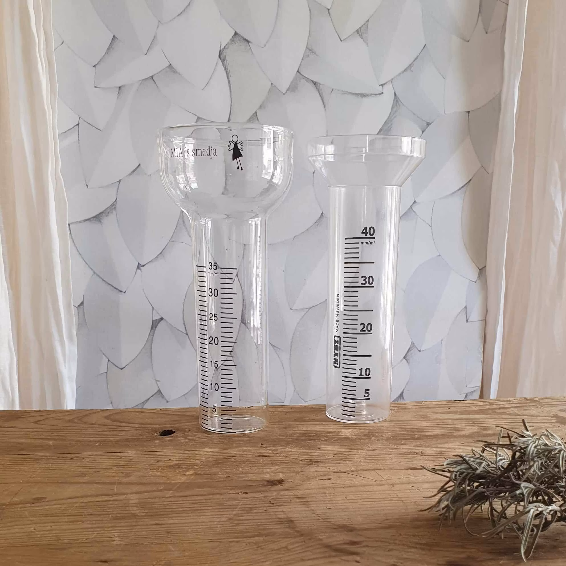 Regnmätarglas i plast och i glas.