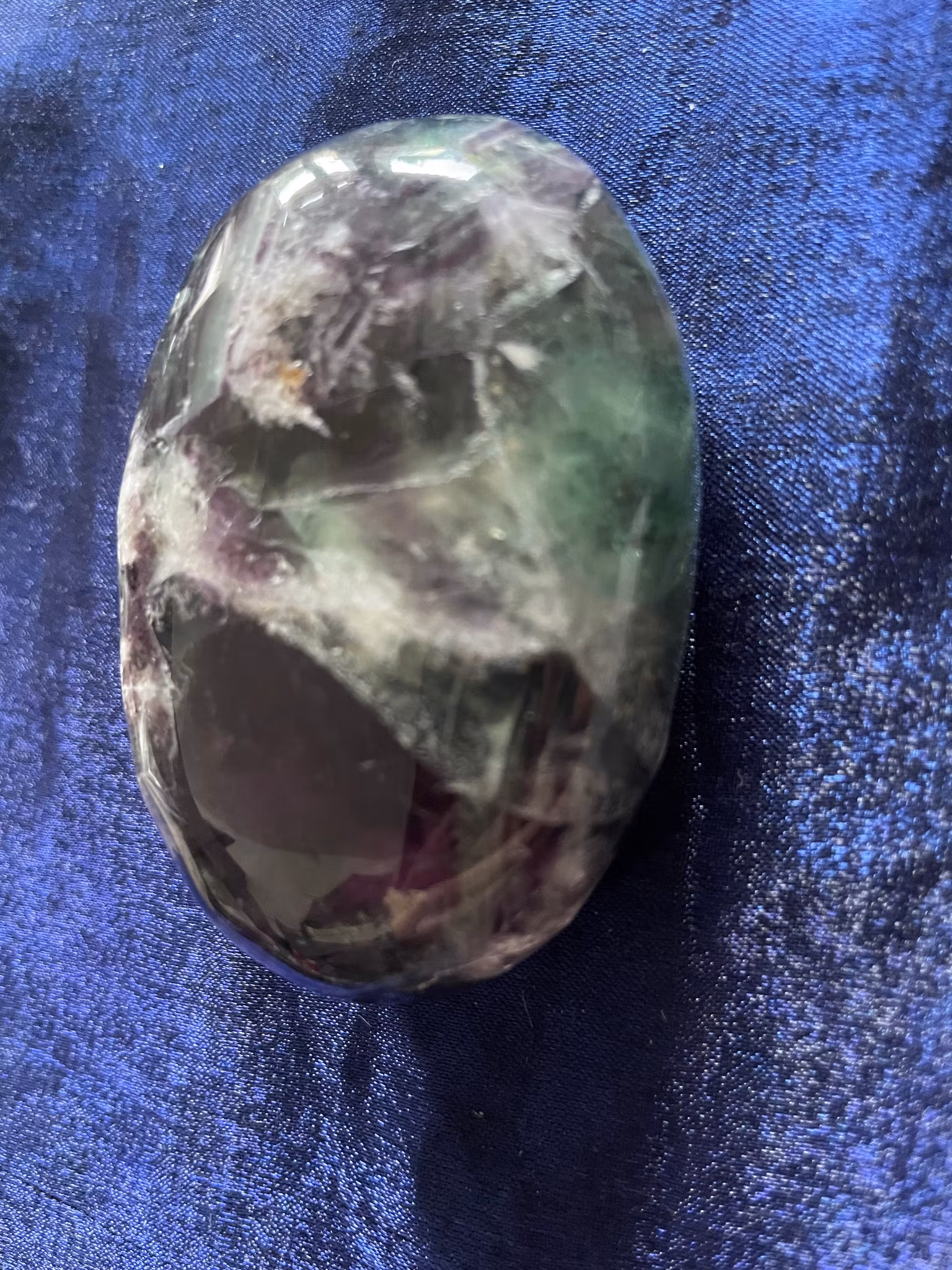 Bilden visar en regnbågsfluorit i palmstone storlek