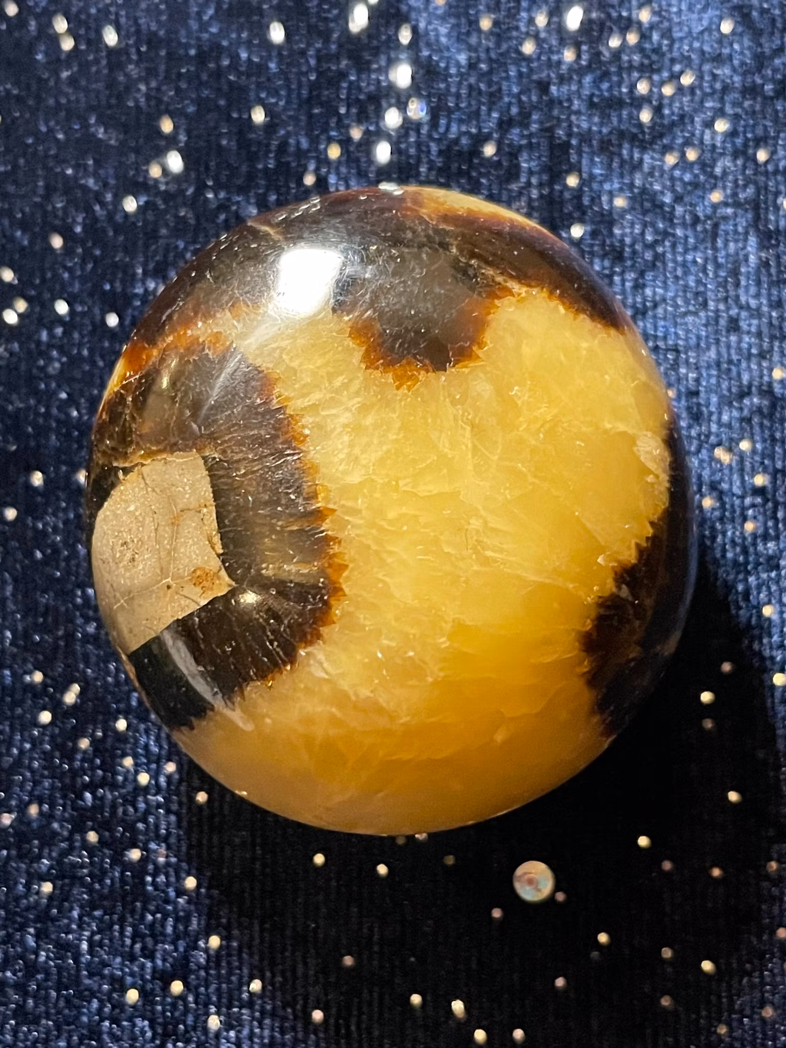 På bilden visas en Draksten (Septarian) . Den är gul med bruna mönster.