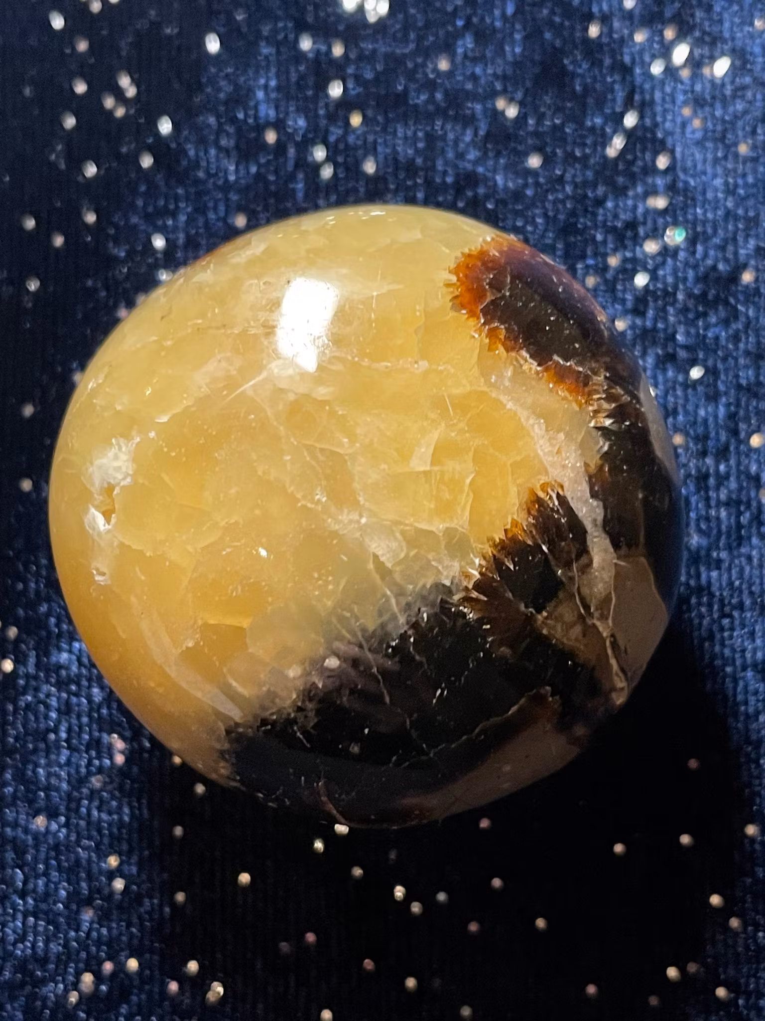 På bilden visas en Draksten (Septarian) . Den är gul med bruna mönster.