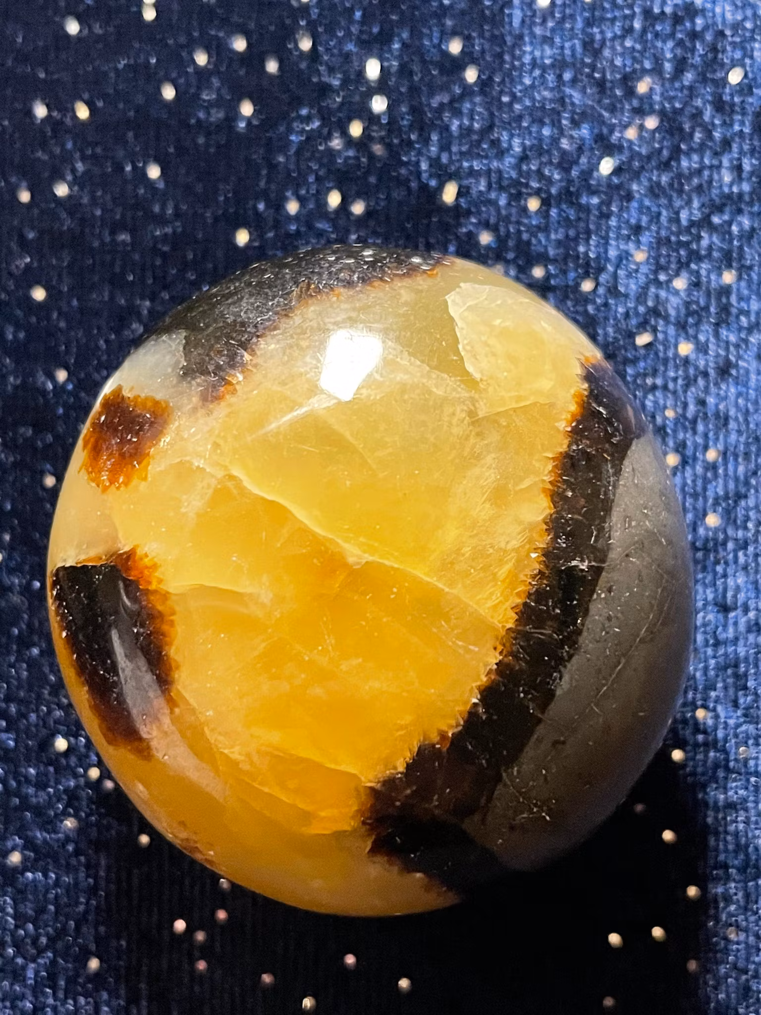 På bilden visas en Draksten (Septarian) . Den är gul med bruna mönster.