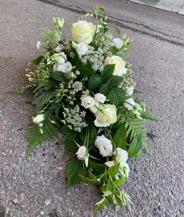 Liggande dekoration med enbart vita blommor och mycket grönt (bilden ca 1200:-)