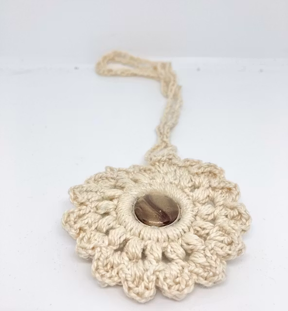 Handgjort virkat halsband med hänge. Material naturfärgat bomullsgarn och brunmelaerad dekorknapp Design JeamsMix hos Ericsson Ur och Guld