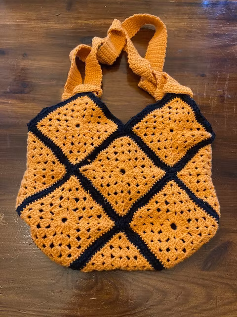 Virkad orange väska dekorerad med svarta virkade rosor och fodrad med svart spets hos Ericsson Ur och Guld Design Jemasmix