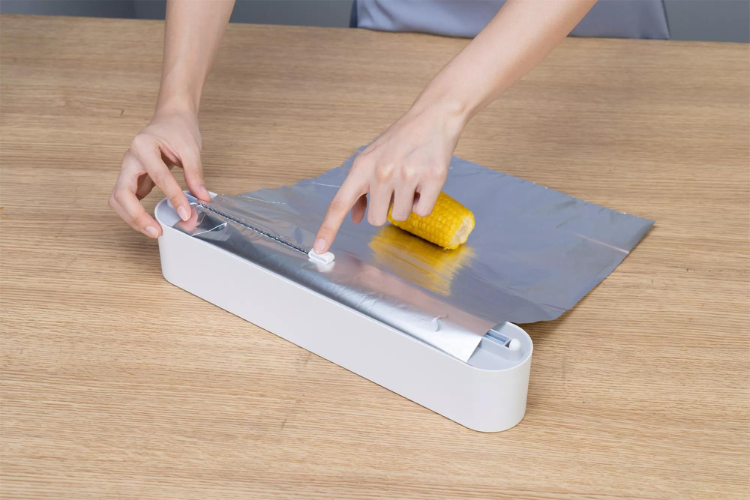 Plastic foil dispenser with sliding cutter
