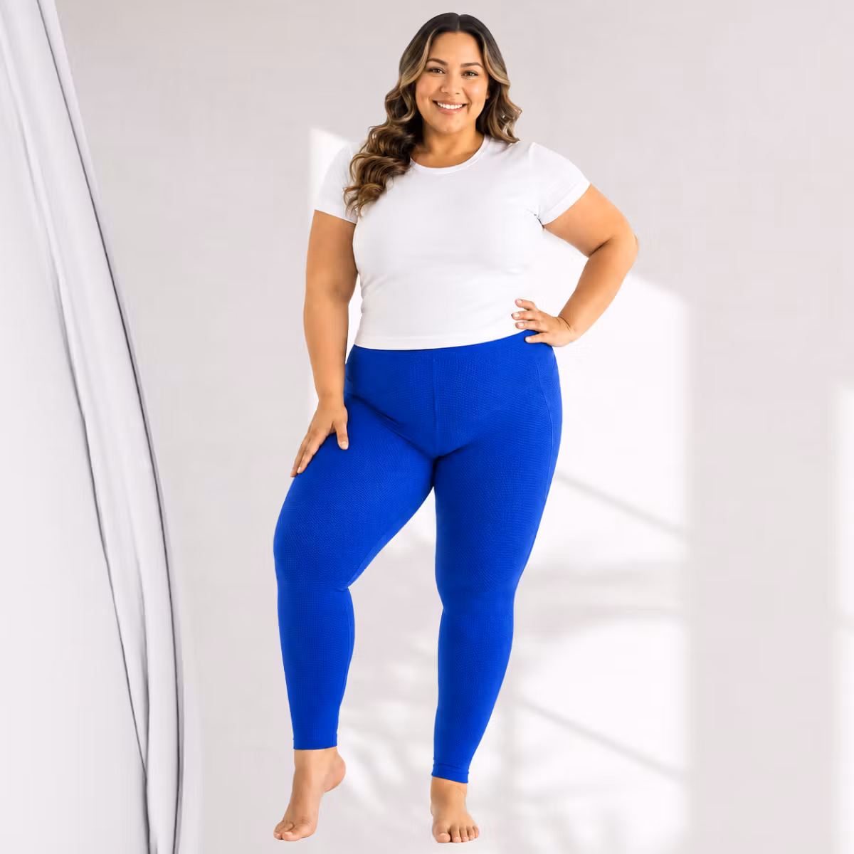 Kurvig kvinna som visar Solidea Be You Tonic Curvy kompressionsleggings i blått tillsammans med en vit T-shirt.