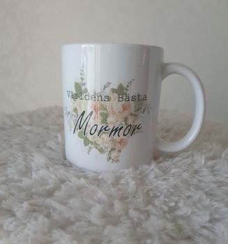 Mugg Världens Bästa Mormor med en blomma bakom.