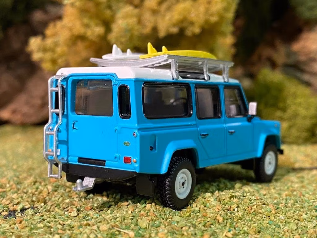 Skala 1/64 Land Rover Defender 110, Ljusblå m räcke & Surfingbräda från MINI GT