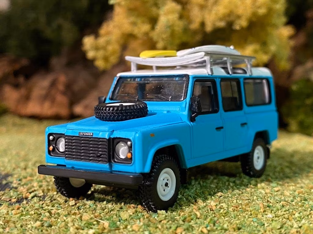 Skala 1/64 Land Rover Defender 110, Ljusblå m räcke & Surfingbräda från MINI GT