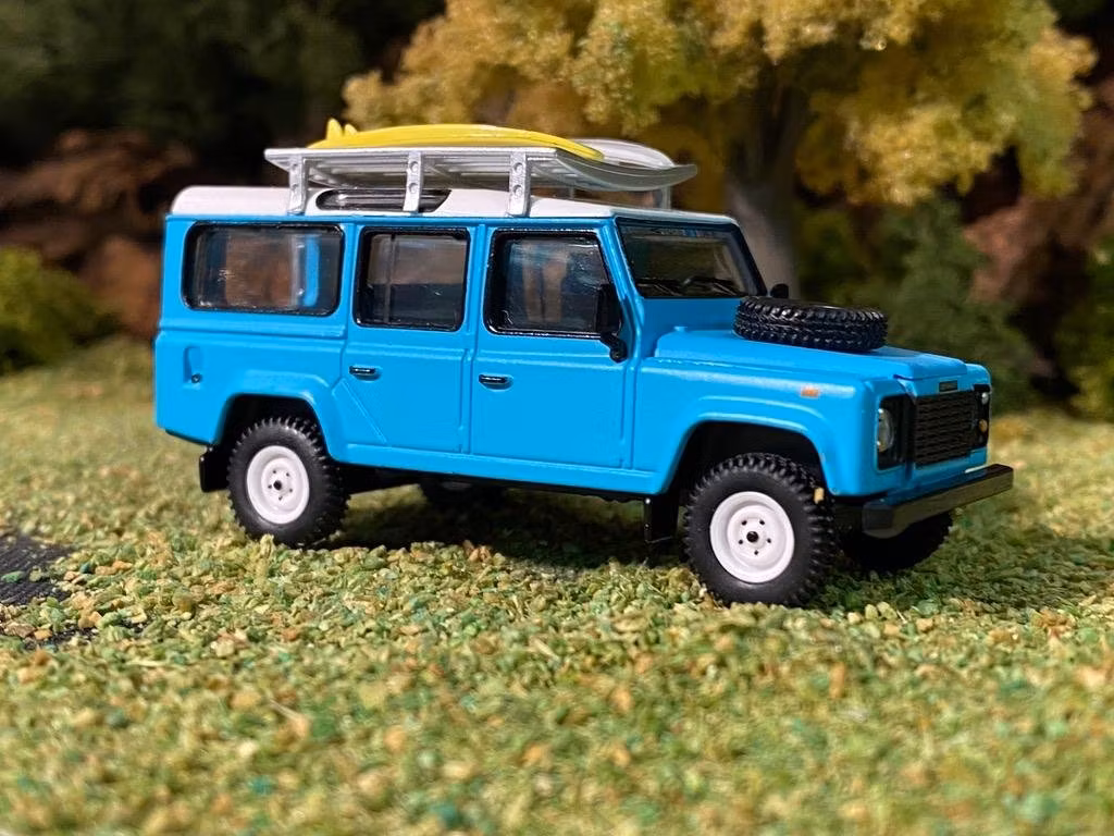 Skala 1/64 Land Rover Defender 110, Ljusblå m räcke & Surfingbräda från MINI GT