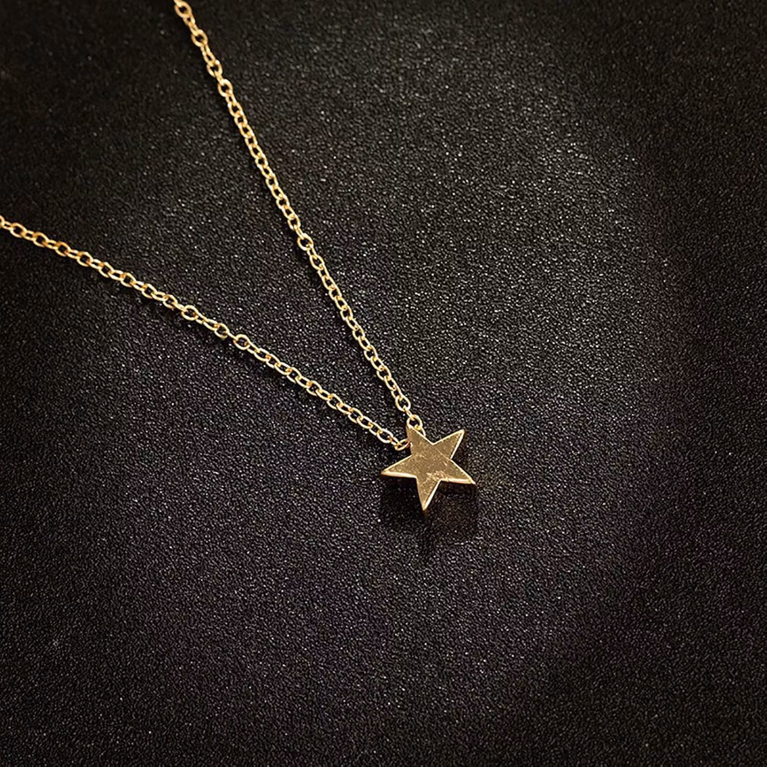Detaljerad bild av en halsband med en liten stjärna, smal kedja och guld färg.