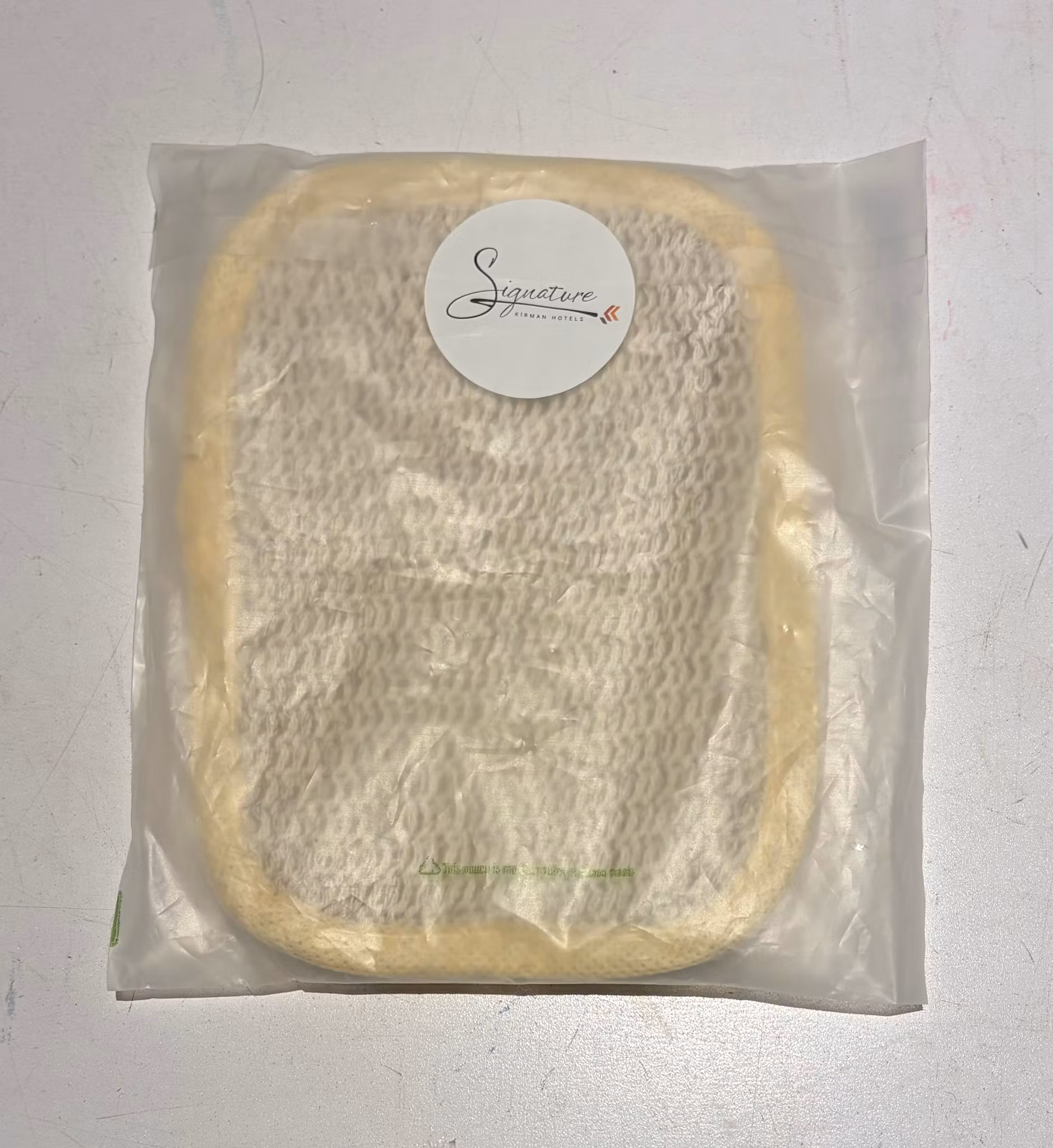 Bagside af Signature by Kirman Hotels peelingpude med håndstrop