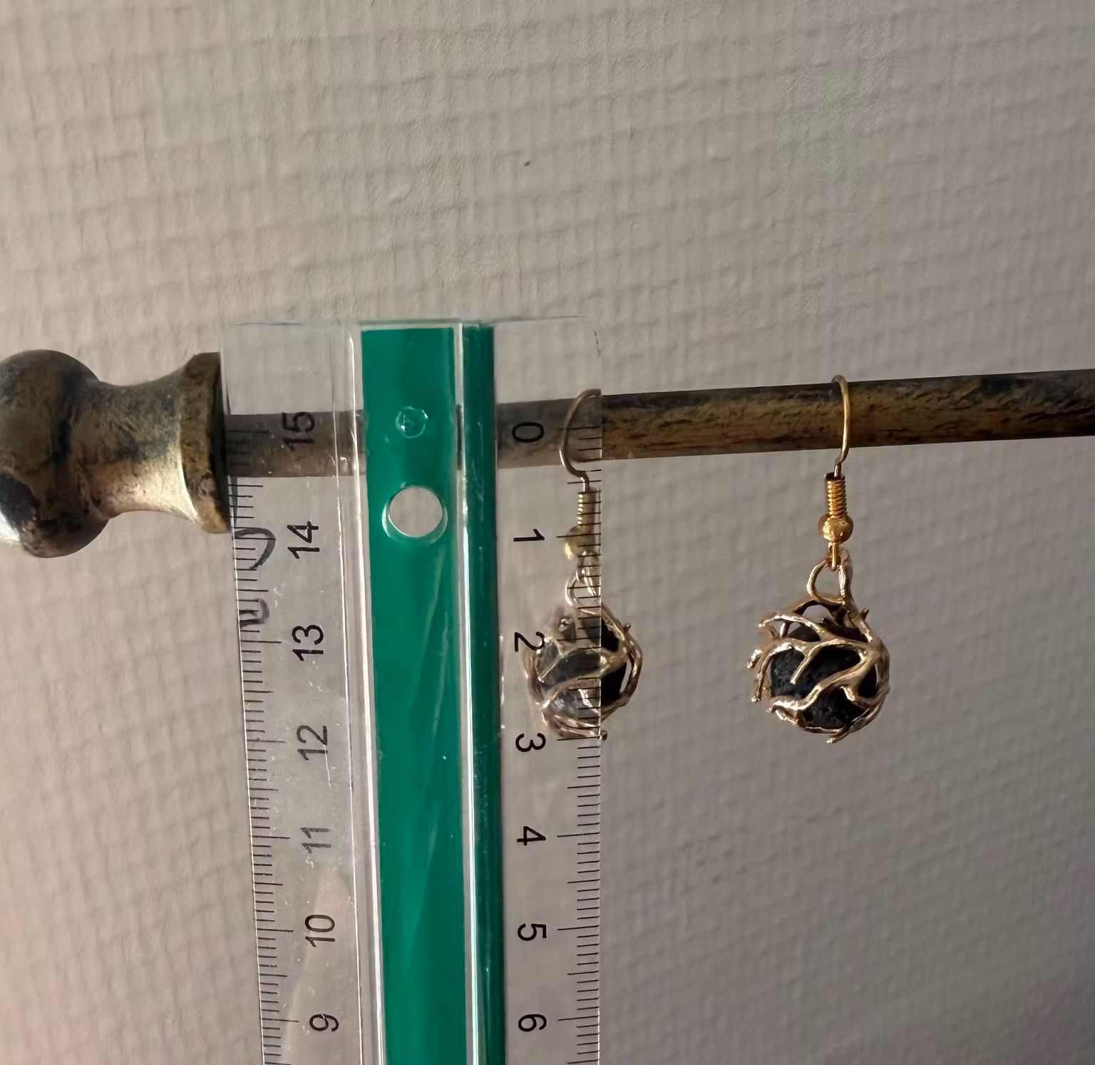 Små guldfarvede øreringe med sorte kuglevedhæng