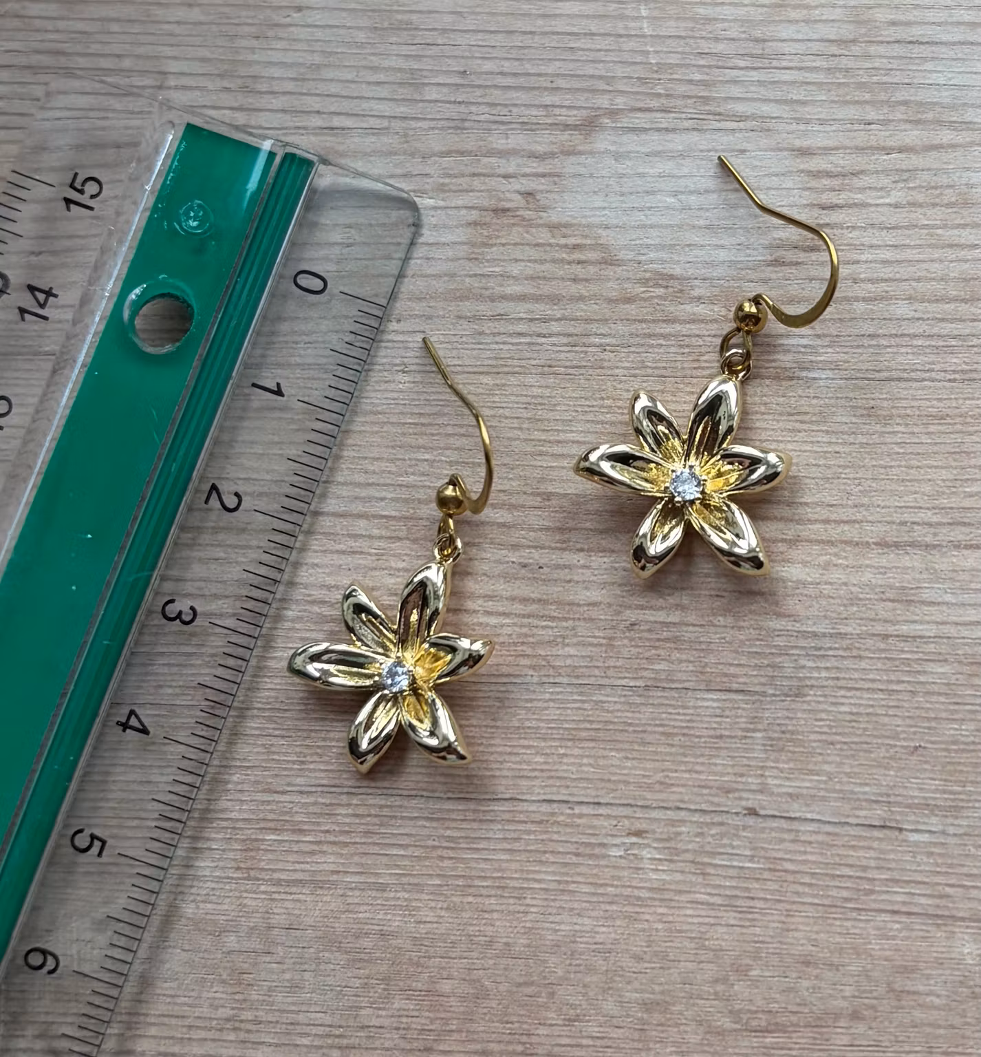 Øreringe med gyldne seksbladede blomster og klare sten – 1 par