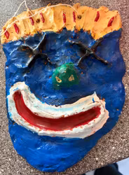 Vægmaske med smil – håndlavet, blå og gul, ca. 25 × 18 cm