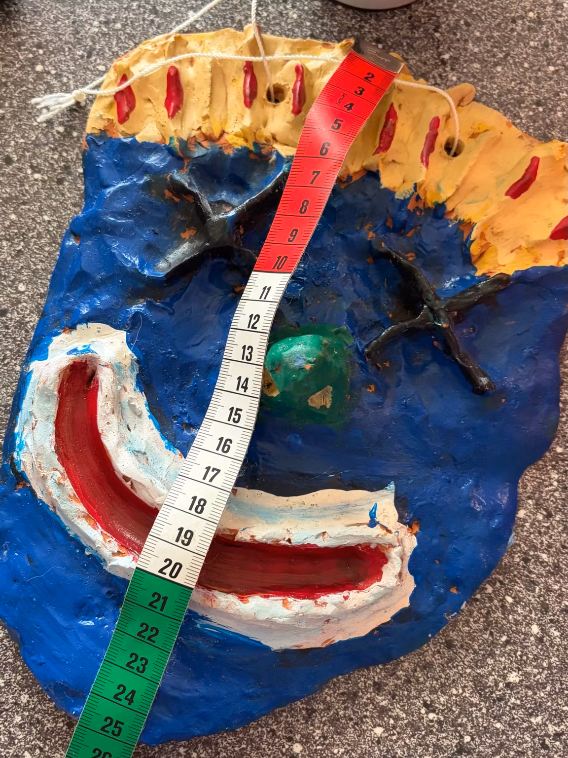 Vægmaske med smil – håndlavet, blå og gul, ca. 25 × 18 cm