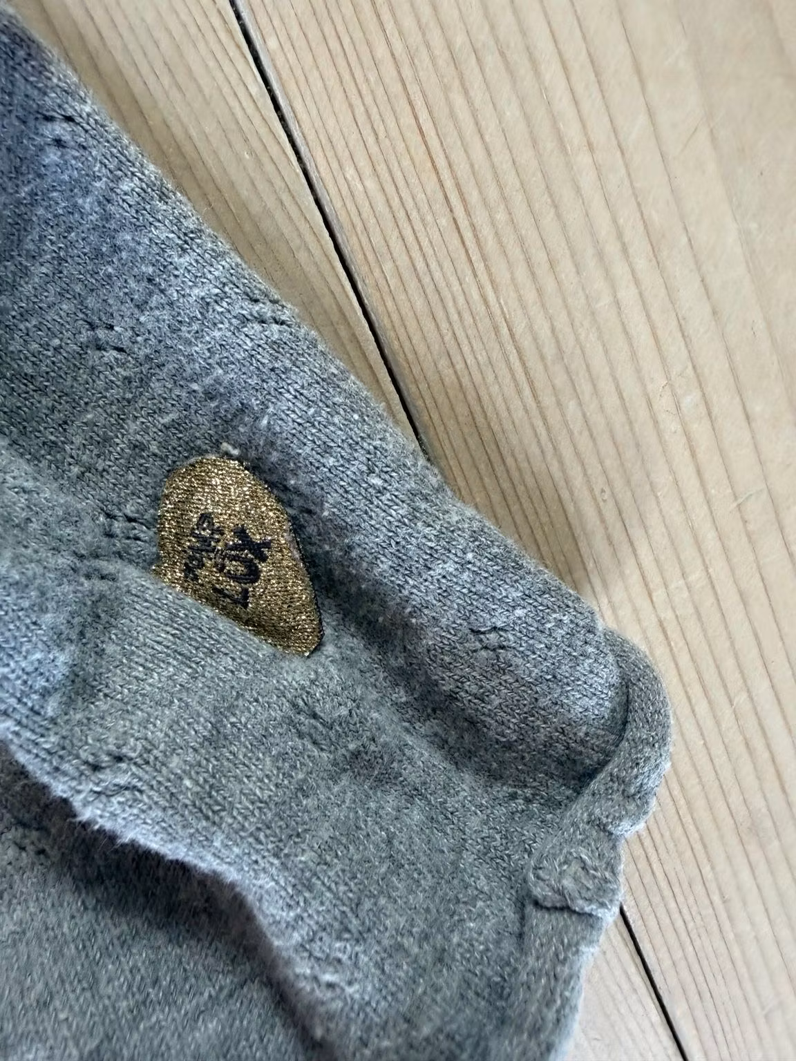 Detalje af strik og guldfarvet hjertemærke