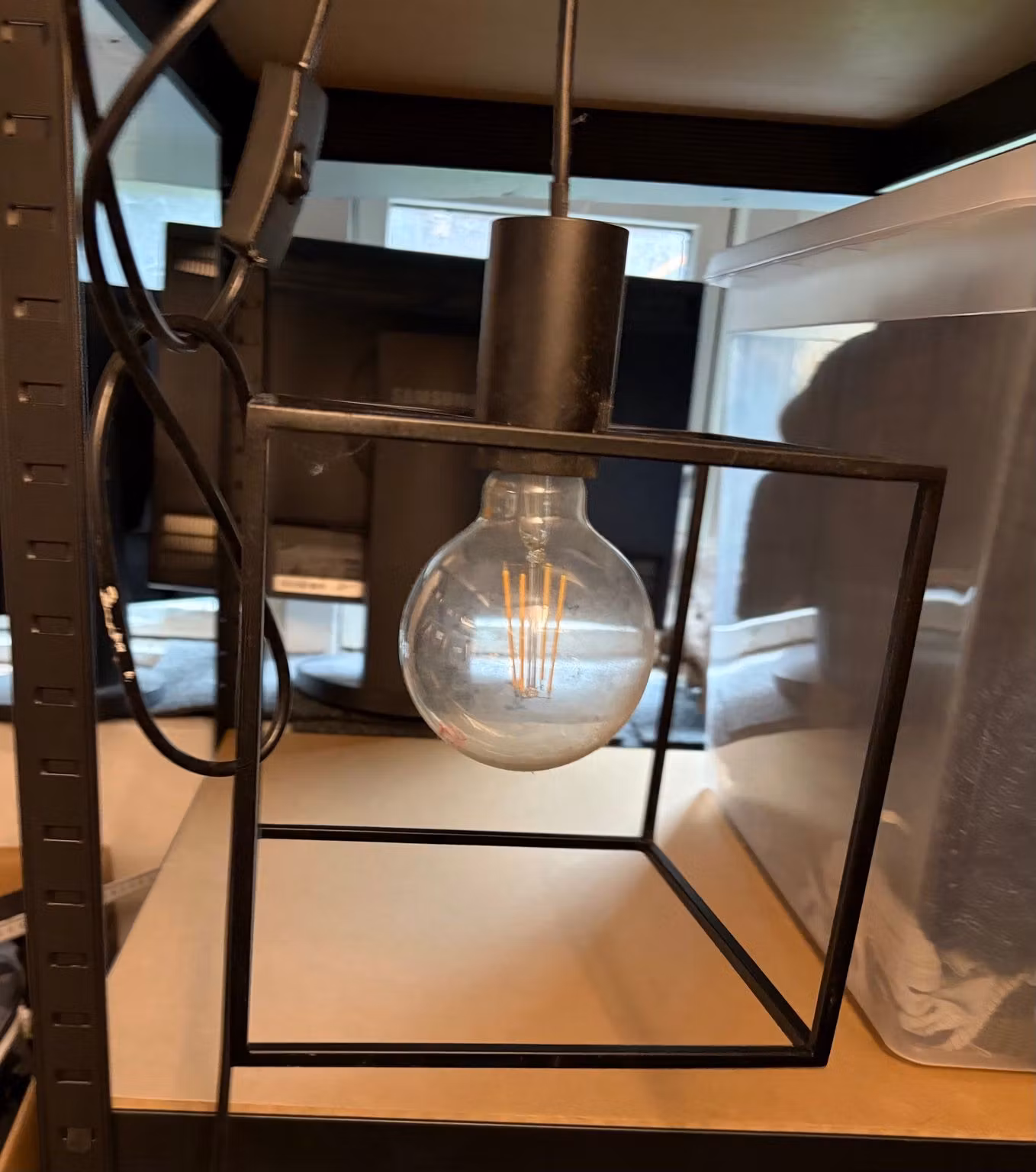 Sort kubelampe med synlig globepære set forfra