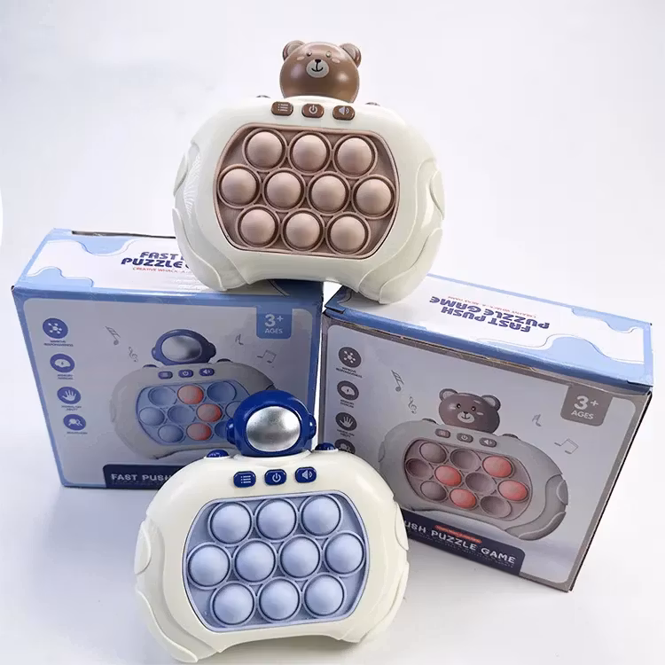 Två interaktiva pop-it leksaker, en med en brun björnfigur och en med en blå astronaut, placerade framför sina förpackningar. Förpackningarna visar leksakernas design och har text