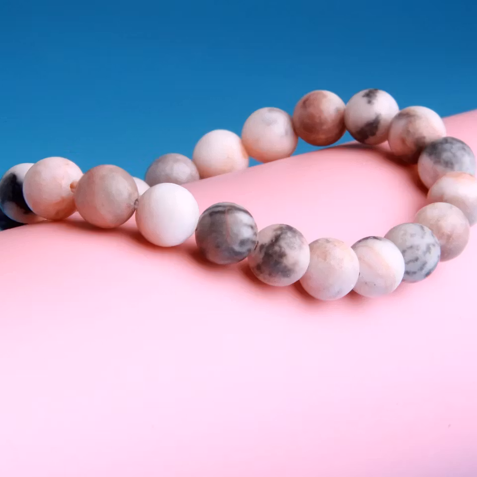 Stilrent armband med 8 mm pärlor av rosa zebrasten, designat för balans och lugn. Färgkombination i rosa, svart och grå.