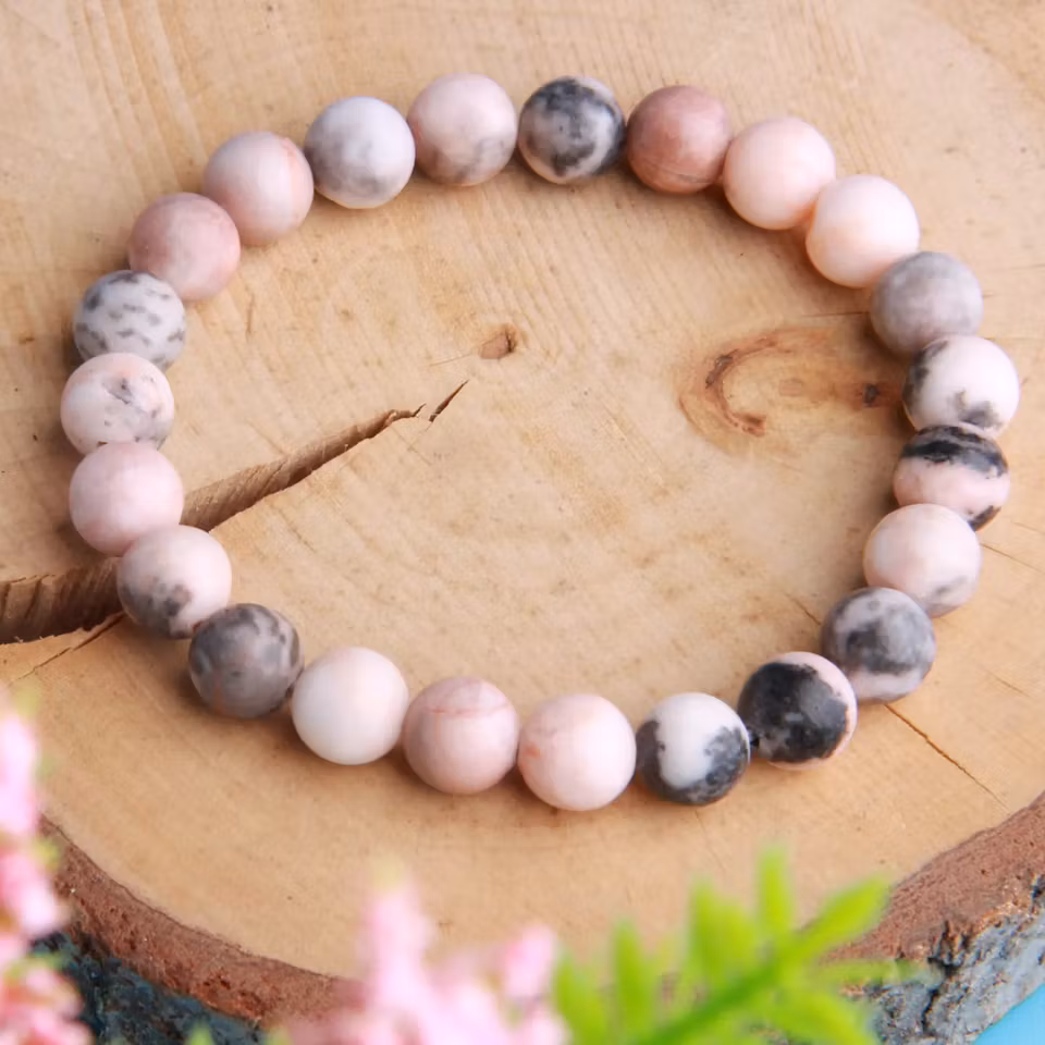 Stilrent armband med 8 mm pärlor av rosa zebrasten, designat för balans och lugn. Färgkombination i rosa, svart och grå.