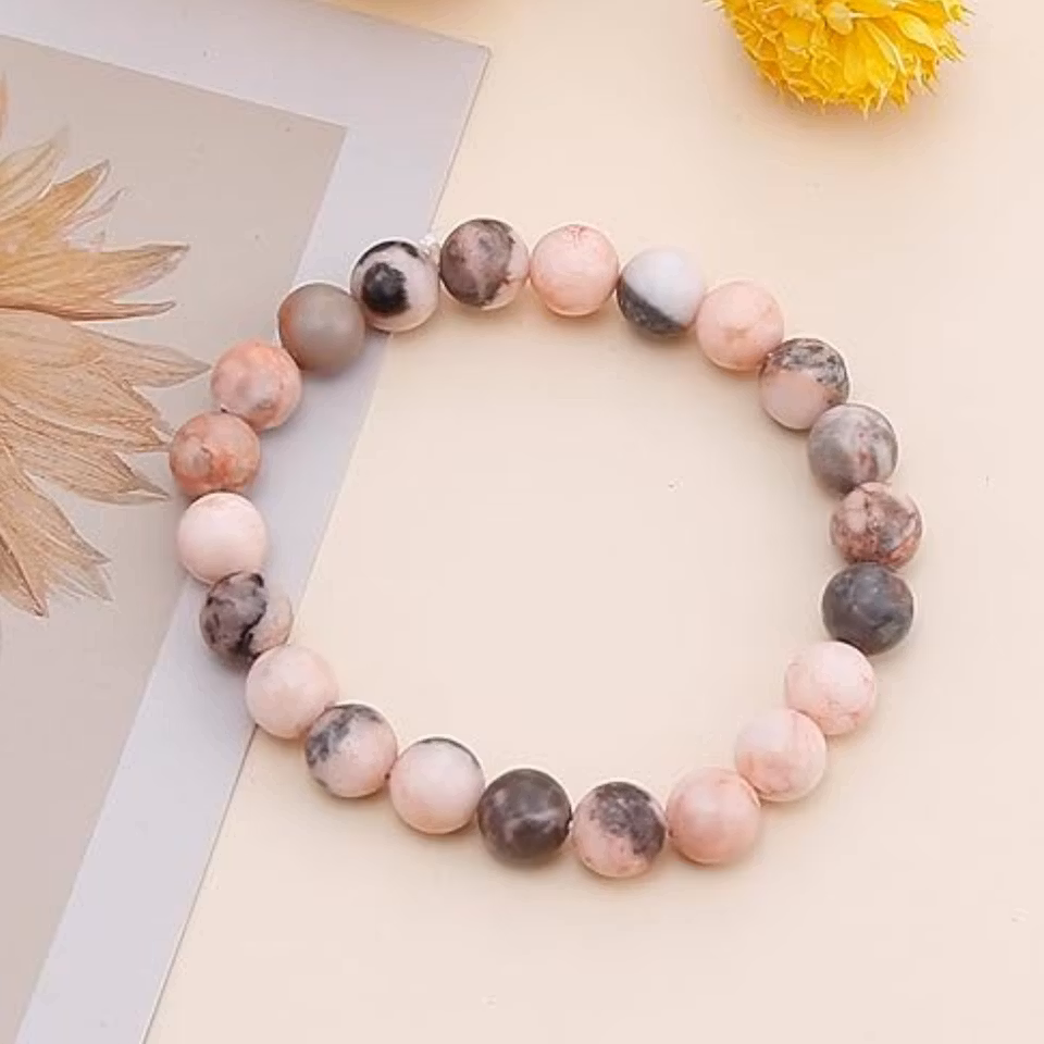 Stilrent armband med 8 mm pärlor av rosa zebrasten, designat för balans och lugn. Färgkombination i rosa, svart och grå.