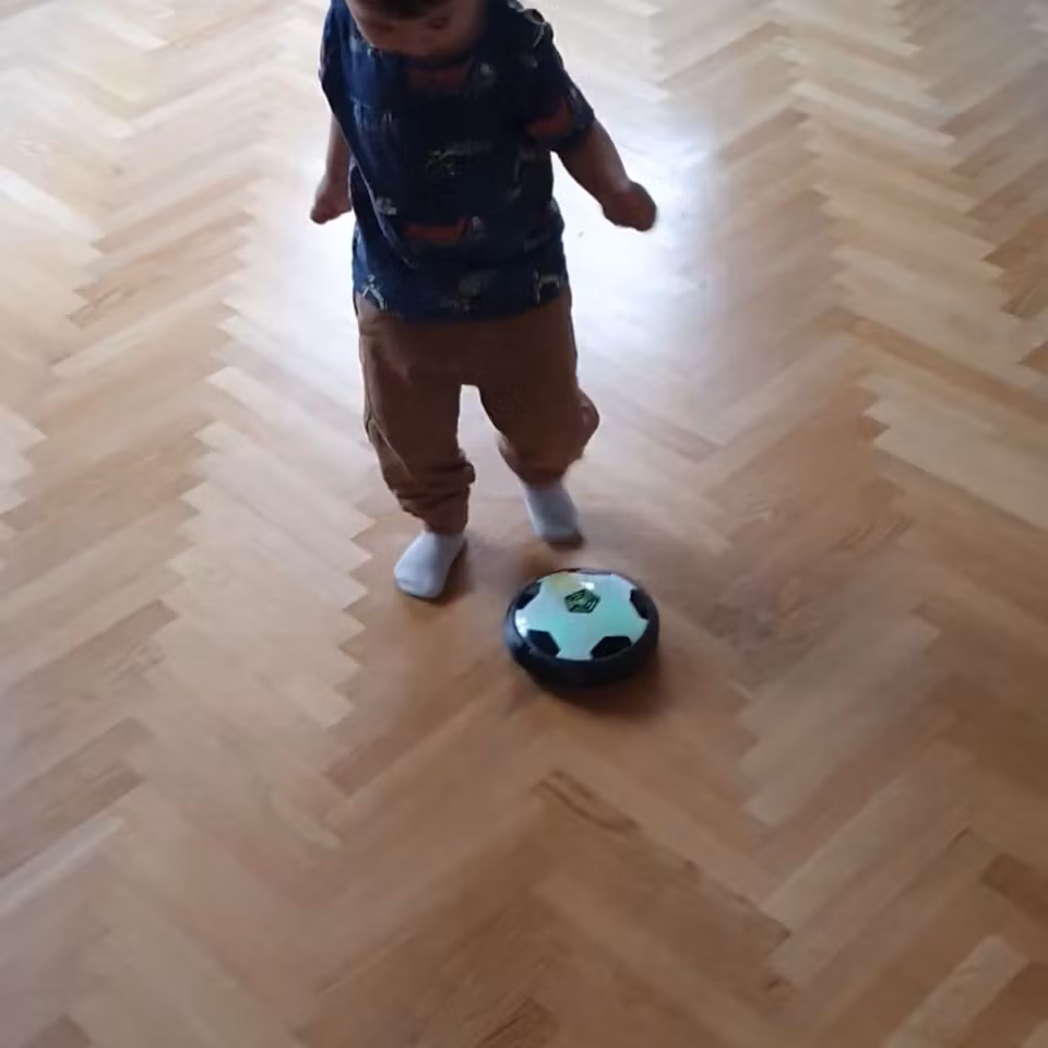 Barn leker med svävande fotboll inomhus – rolig och säker leksak för aktiv lek hemma.