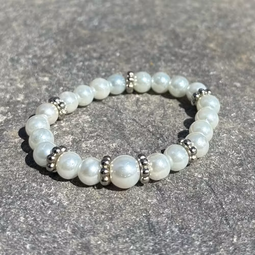 Armband med vita glaskulor och silvriga detaljer