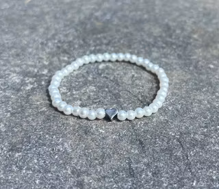 Vitt armband med glaskulor och ett silvrigt hjärta