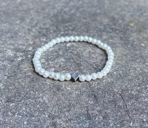 Vitt armband med glaskulor och ett silvrigt hjärta