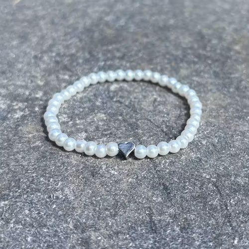 Vitt armband med glaskulor och ett silvrigt hjärta
