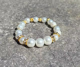 Armband med vita glaskulor och guldiga detaljer