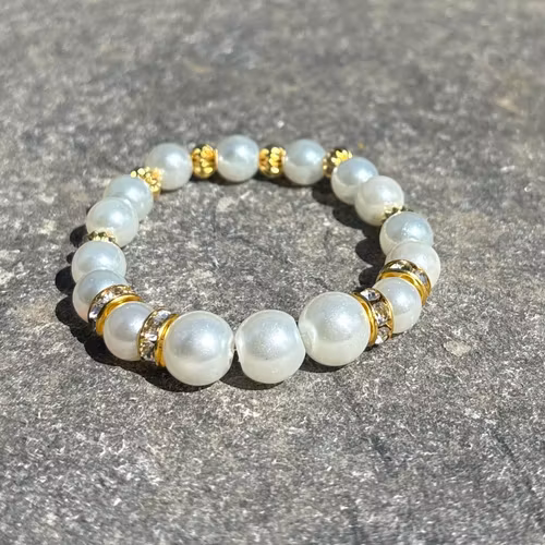 Armband med vita glaskulor och guldiga detaljer