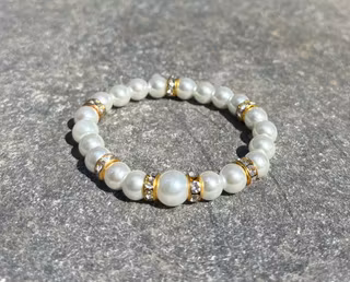 Armband med vita glaskulor och guldiga detaljer 1