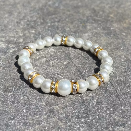 Armband med vita glaskulor och guldiga detaljer 1