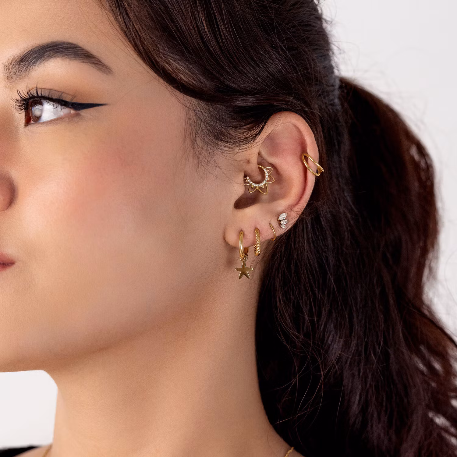 Clickerring i guldig färg med vit strass och blomliknande detaljer 1,2x8 mm