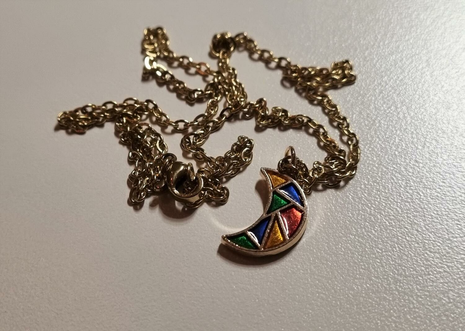 Guldfärgat halsband med en månformad berlock / charm