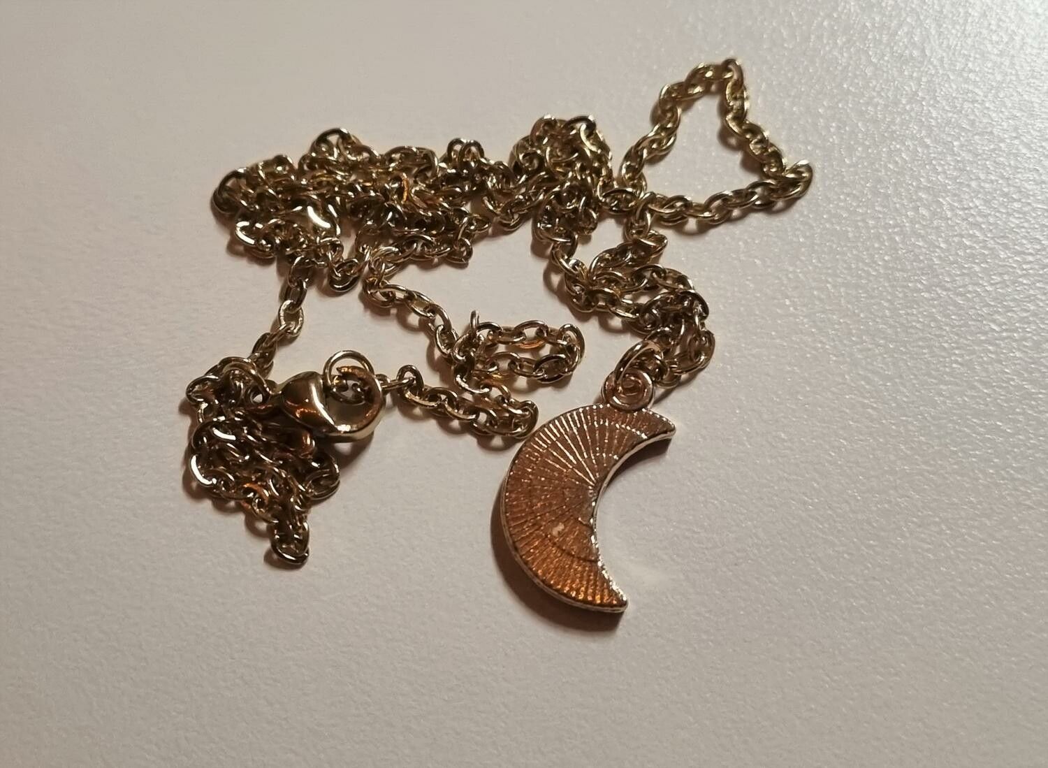 Guldfärgat halsband med en månformad berlock / charm