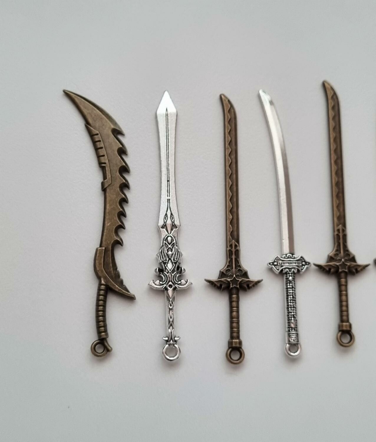 10 st berlocker - Miniatyrvapen, minisvärd, treuddar med mera. Fina miniatyrer