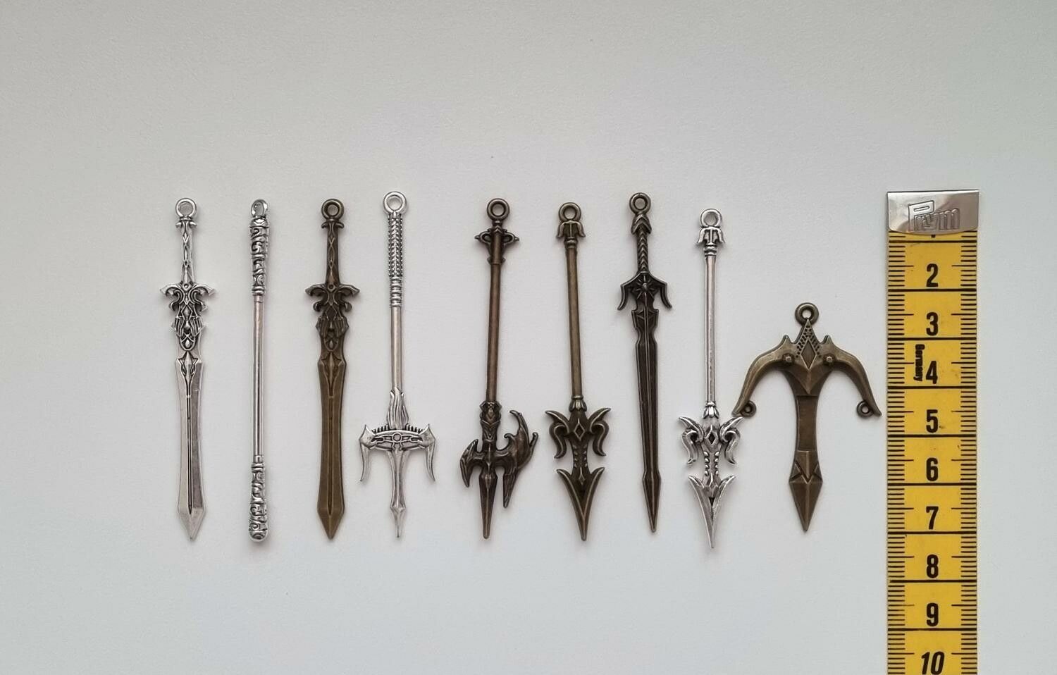 9 st berlocker - Miniatyrvapen, minisvärd, treuddar med mera. Fina miniatyrer