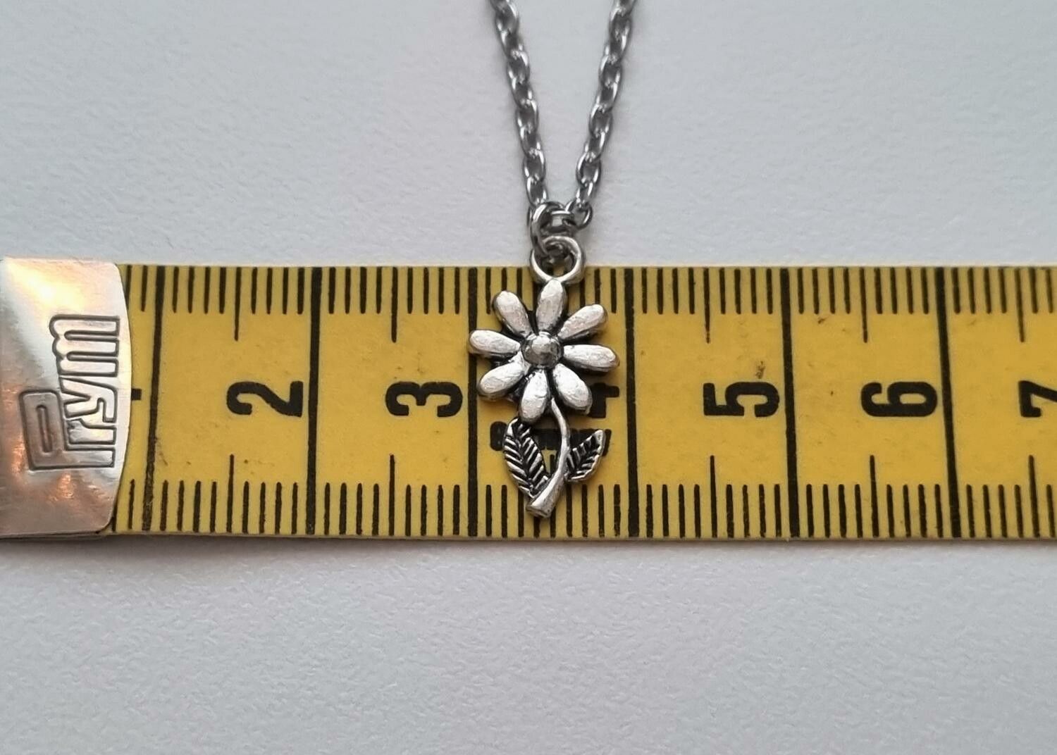 Silverfärgat halsband med en blomma, berlock / charm