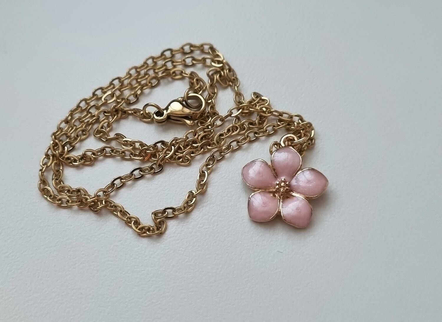 Guldfärgat halsband med en rosa blomma, blomberlock / charm